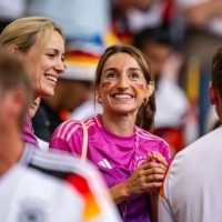 Lena Wurzenberger auf der Tribüne bei einem Spiel der deutschen Nationalmannschaft mit aufgemalten Deutschland-Flaggen auf der Wange.